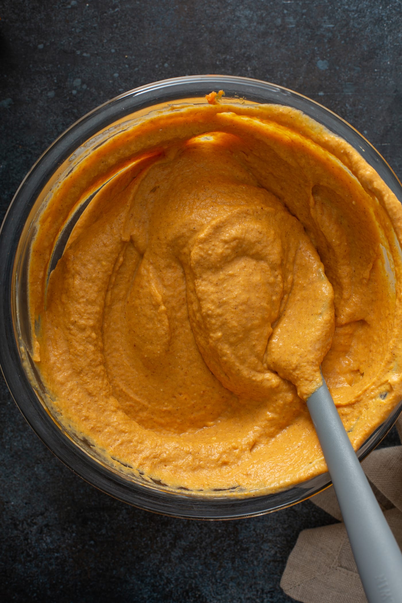 Pumpkin cheesecake filling in a bowl with a spoon.