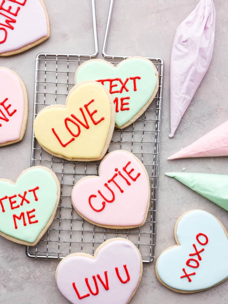 Valentine's day cookies on a cooling rack with fun sayings on them like text me and cutie.
