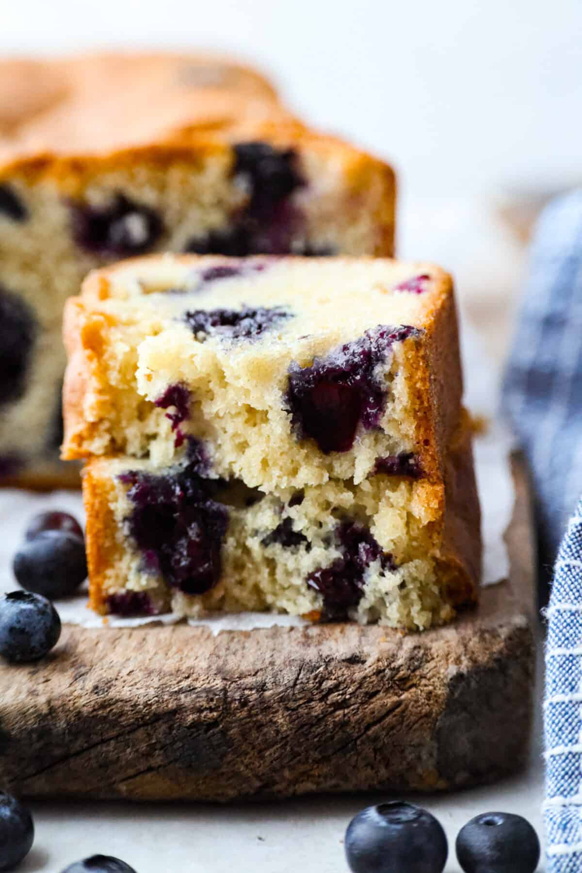 Close up shot of a slice of a 5 ingredient blueberry bread slice cut in hlaf ans stacked. 