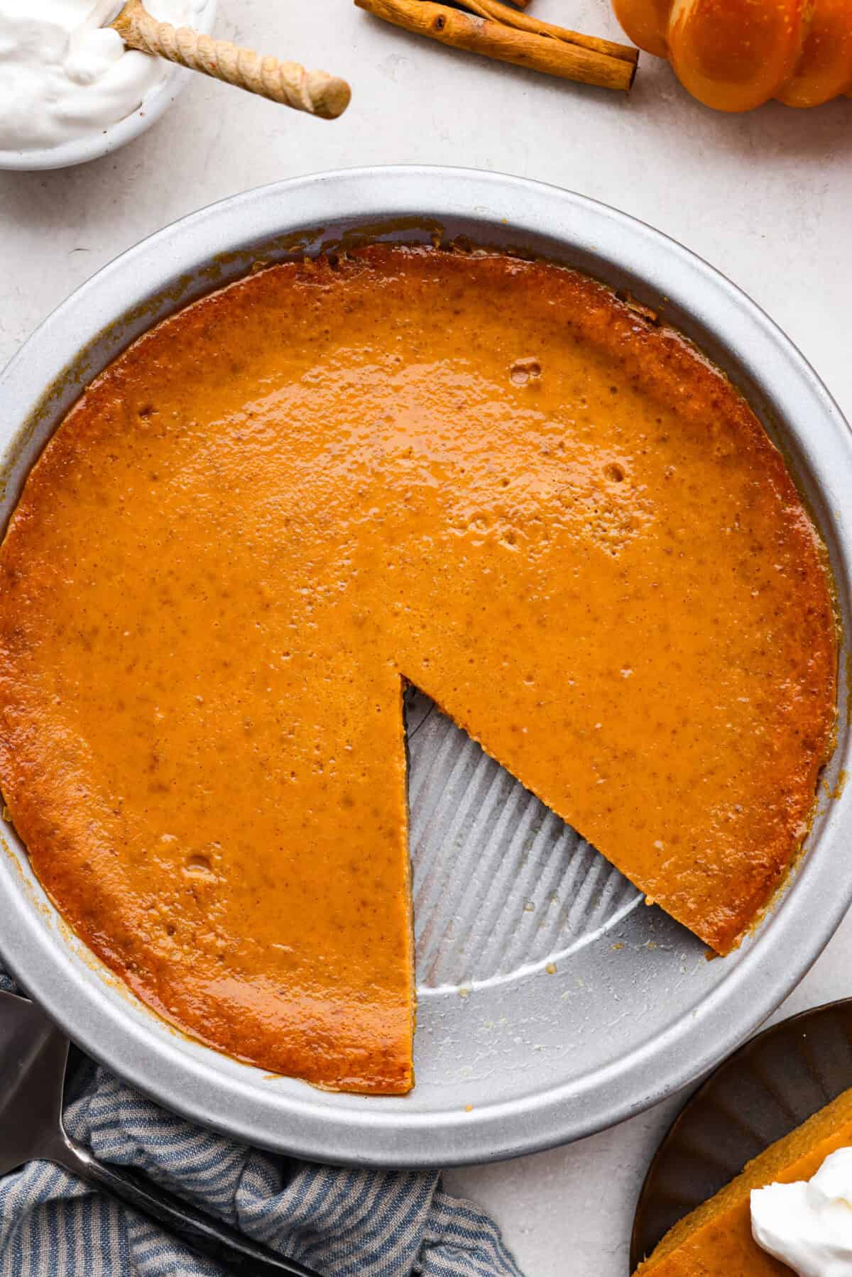 Overhead shot of a crustless pumpkin pie with a slice taken out. 