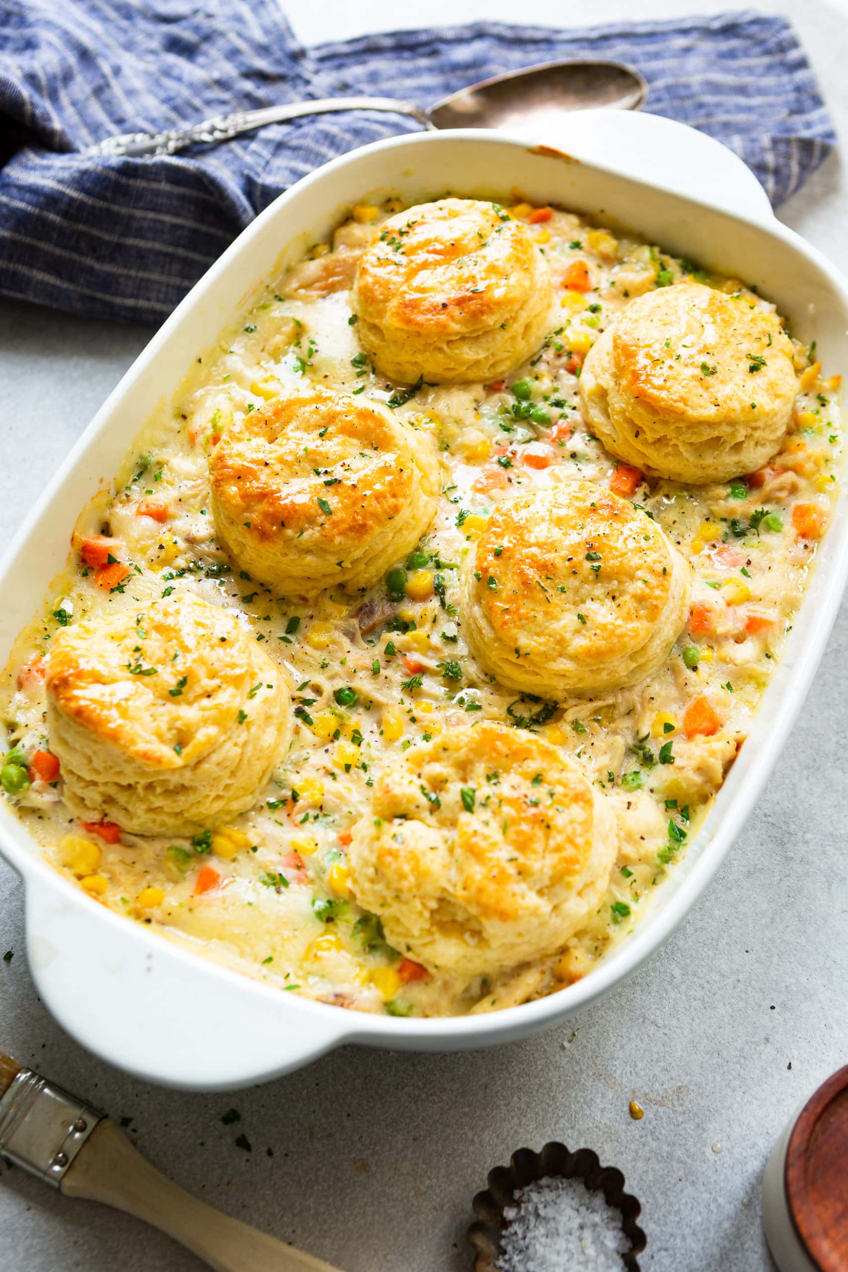 a photo of a white rectangular baking dish full of creamy chicken pot pie that is full of veggies and chunks of chicken with a golden biscuit topping.