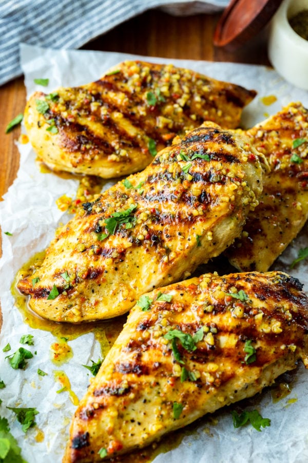 a photo of several golden grilled chicken breasts that look juicy and have perfect diagonal grill marks on them. a photo of several golden grilled chicken breasts that look juicy and have perfect diagonal grill marks on them.
