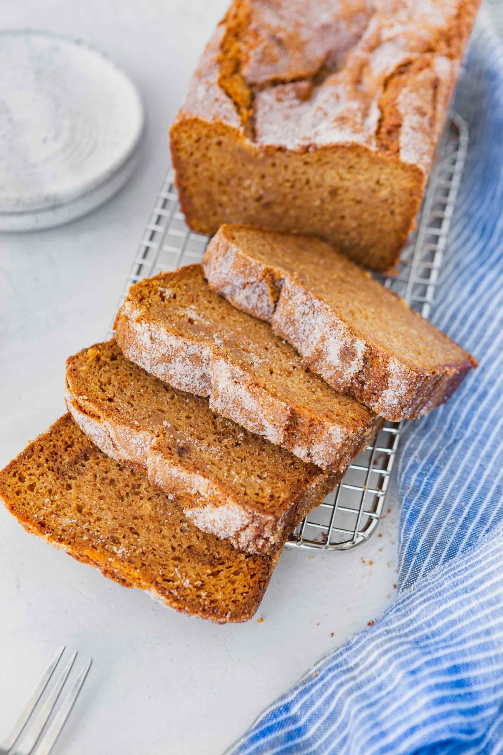 a photo of a loaf of baked amish friendship bread topped with cinnamon and sugar and half of the loaf cut into thick slices. a photo of a loaf of baked amish friendship bread topped with cinnamon and sugar and half of the loaf cut into thick slices.