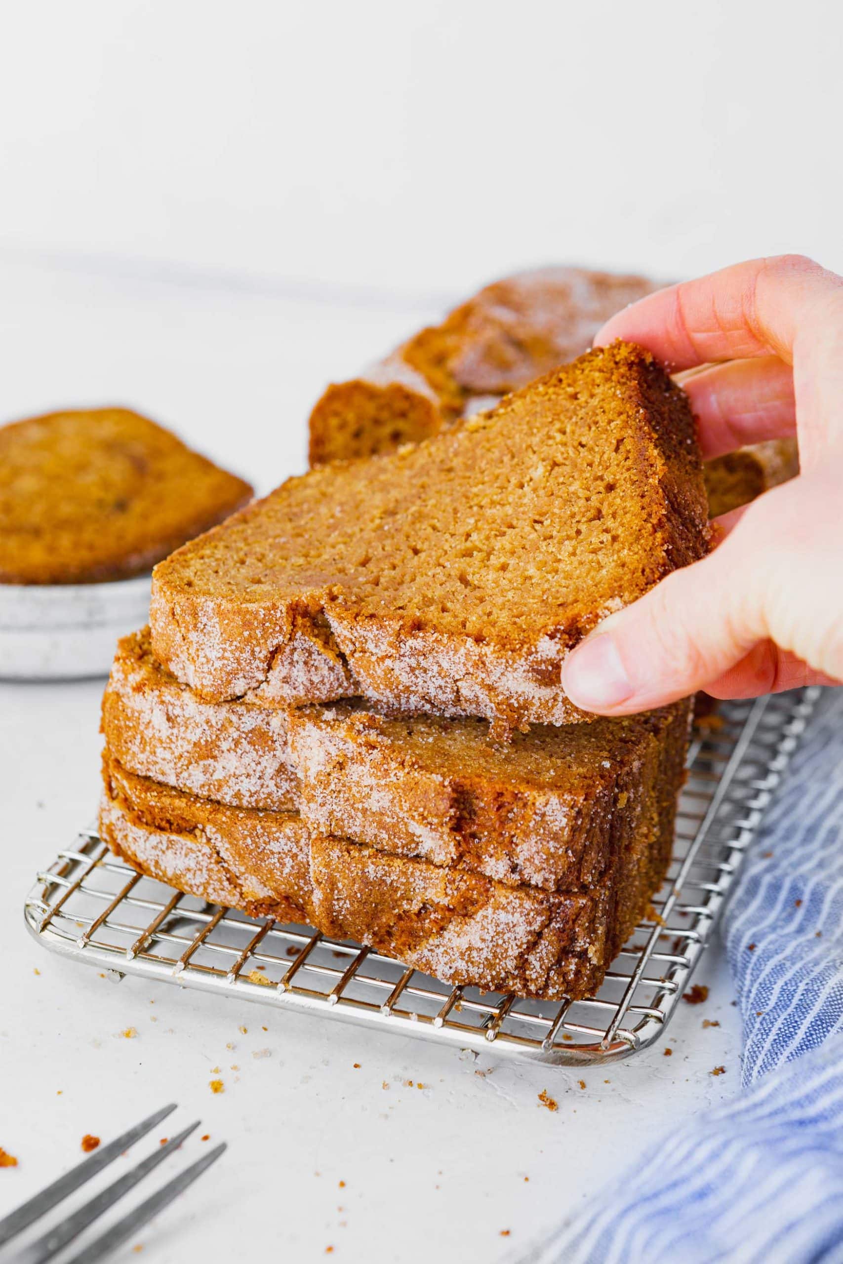 a photo of a stack of slices of amish friendship bread with someone's hand grabbing the top slice from the stack. a photo of a stack of slices of amish friendship bread with someone's hand grabbing the top slice from the stack.