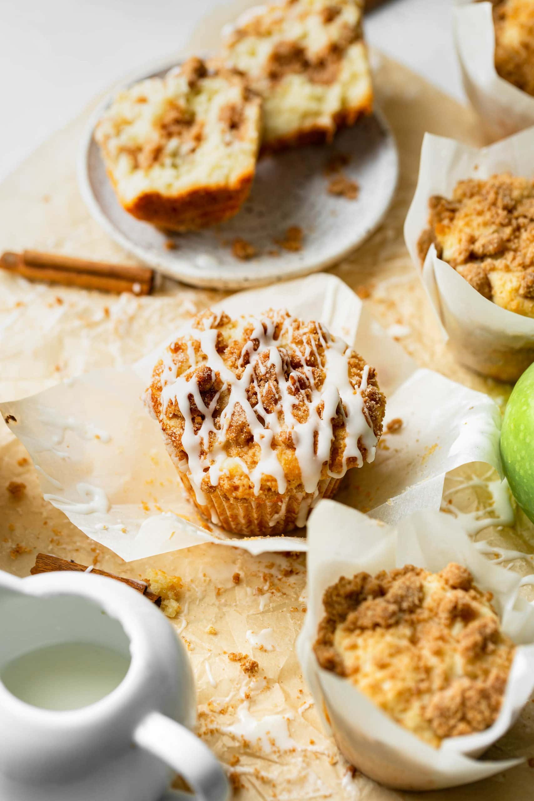a photo of a coffee cake muffin sitting in the wrapper it has been removed from surrounded by other muffins still in the wrapper. a photo of a coffee cake muffin sitting in the wrapper it has been removed from surrounded by other muffins still in the wrapper.