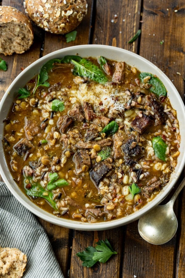 a photo of a soup bowl full of beef barley soup with chunks of tender beef, pearl barley, wild rice and spinach. a photo of a soup bowl full of beef barley soup with chunks of tender beef, pearl barley, wild rice and spinach.
