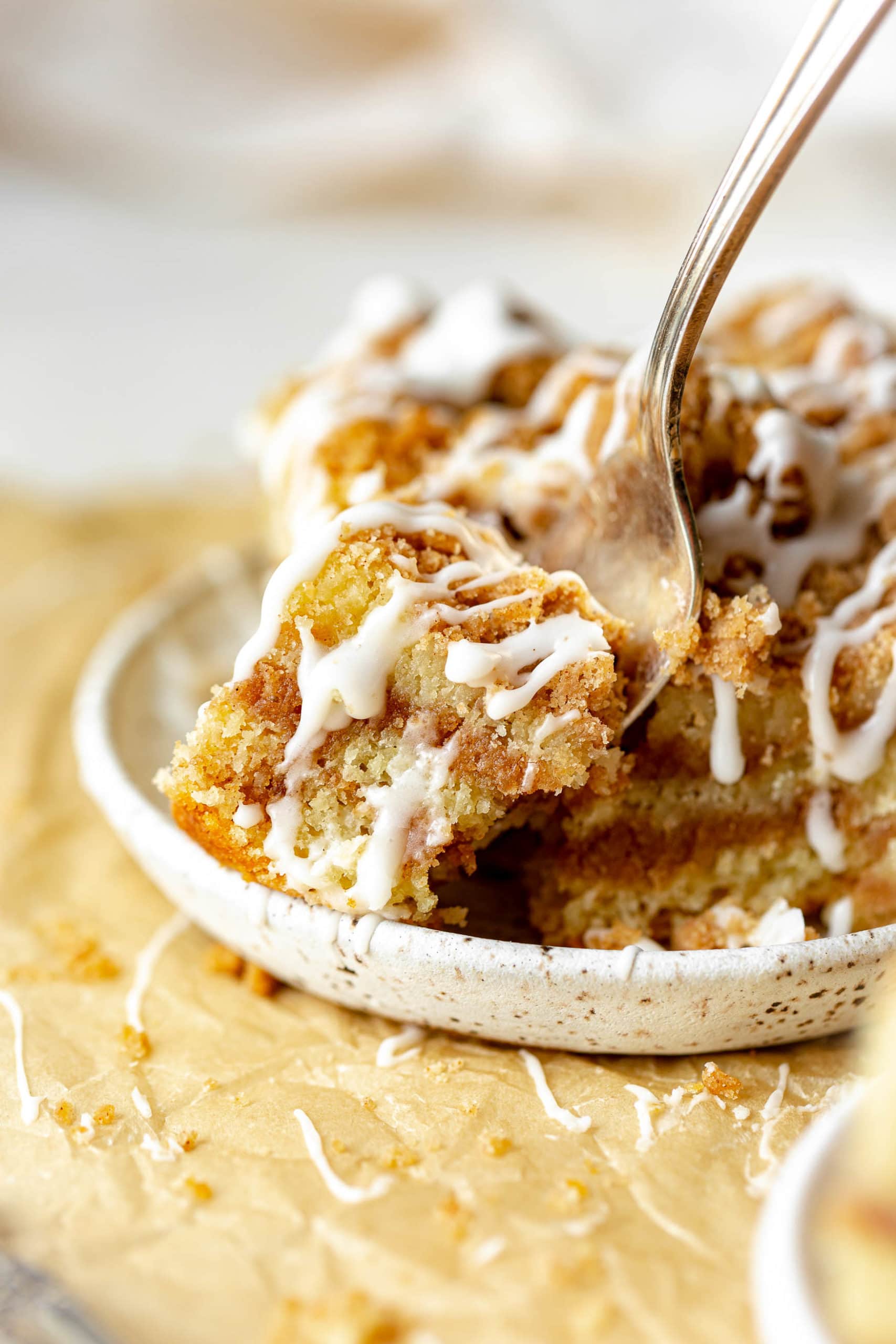 a photo of a fork removing a bite from the corner of a piece of moist perfect coffee cake. a photo of a fork removing a bite from the corner of a piece of moist perfect coffee cake.