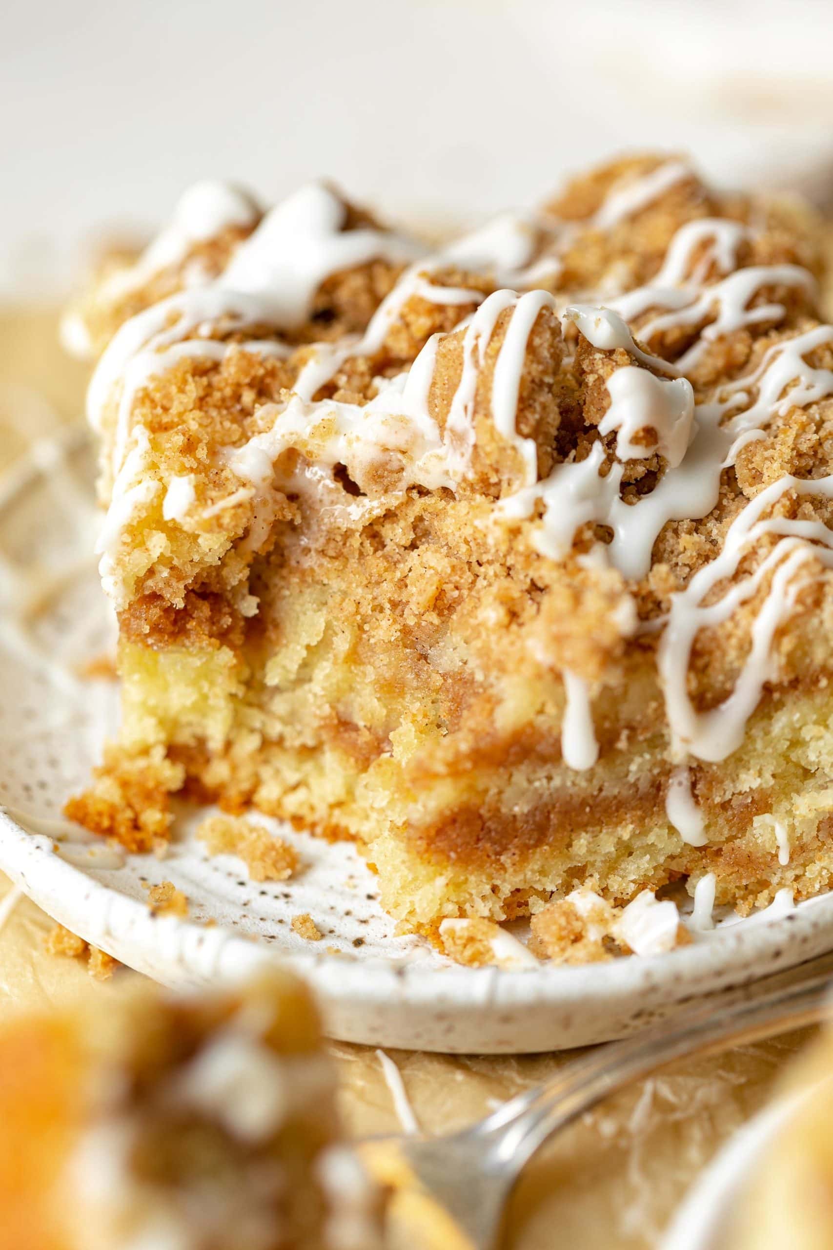 a closeup photo of a piece of moist tender coffee cake with a bite taken out of the corner. a closeup photo of a piece of moist tender coffee cake with a bite taken out of the corner.
