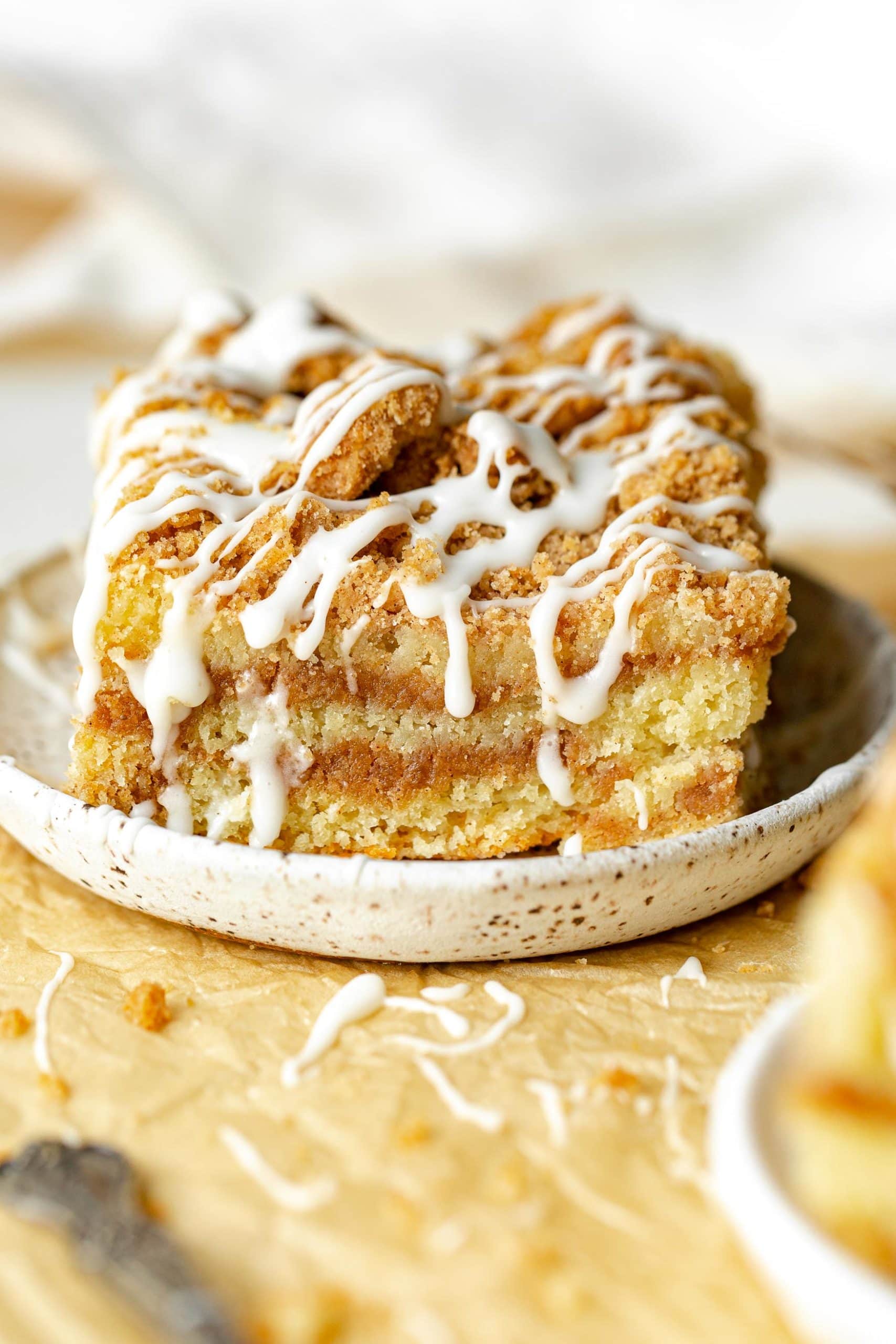 a photo of a single piece of coffee cake on a small saucer topped with a drizzle of icing. a photo of a single piece of coffee cake on a small saucer topped with a drizzle of icing.