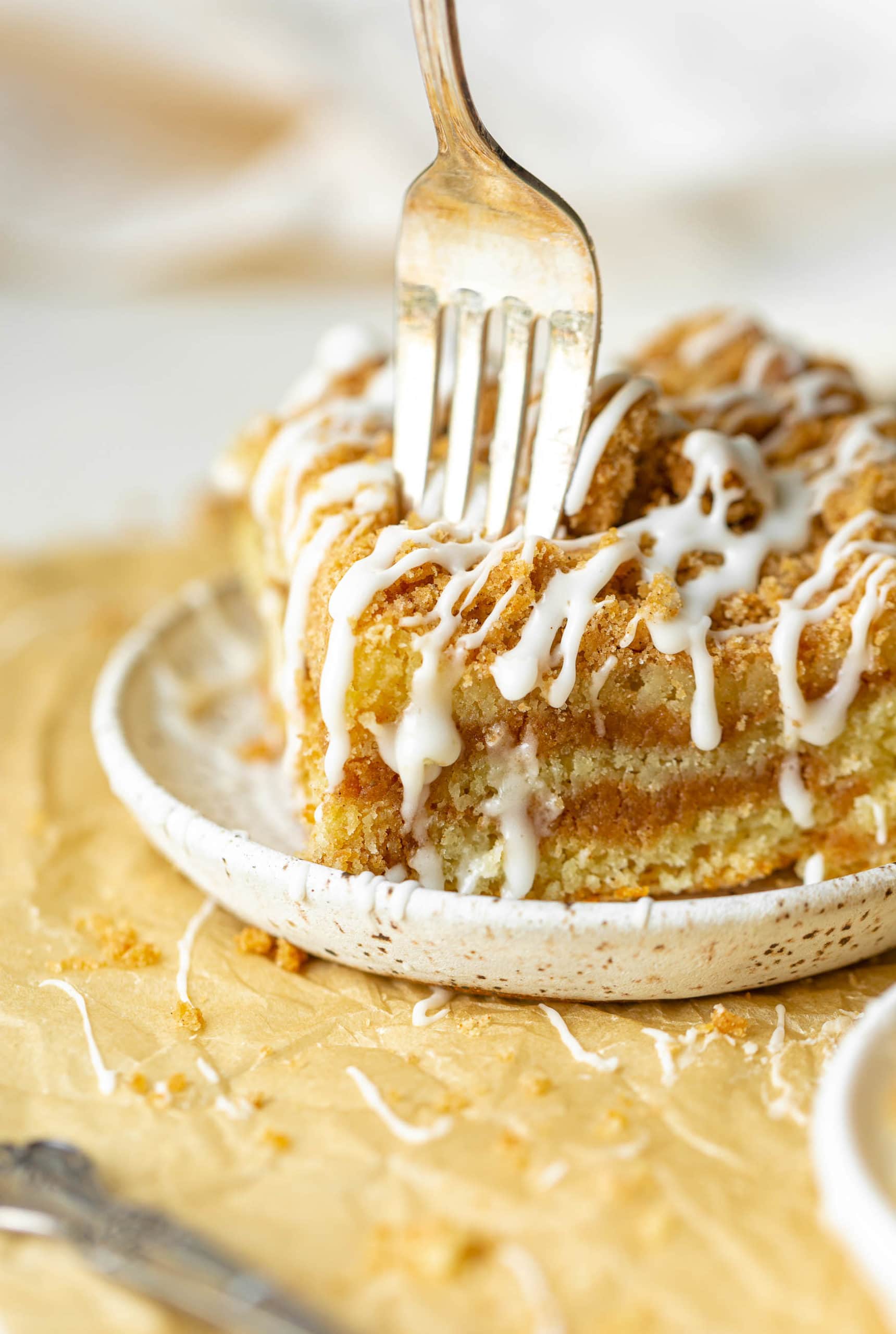 a photo of a fork being stuck into the corner of a piece of coffee cake. a photo of a fork being stuck into the corner of a piece of coffee cake.
