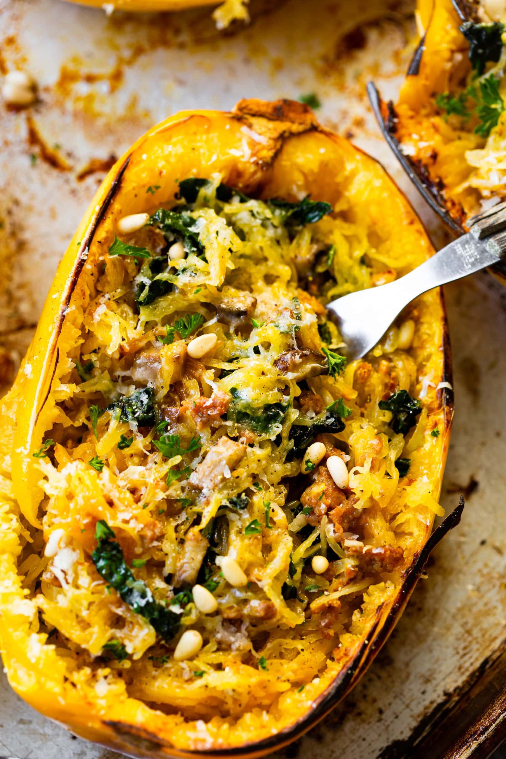 a photo of a roasted spaghetti squash stuffed with kale, baby bella mushrooms, garlic, pine nuts and topped with parmesan cheese and fresh parsley. a photo of a roasted spaghetti squash stuffed with kale, baby bella mushrooms, garlic, pine nuts and topped with parmesan cheese and fresh parsley.