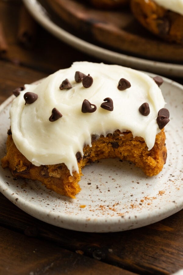 a photo of thick pumpkin chocolate chip cookie topped with cream cheese frosting and sprinkled with mini chocolate chips a photo of thick pumpkin chocolate chip cookie topped with cream cheese frosting and sprinkled with mini chocolate chips