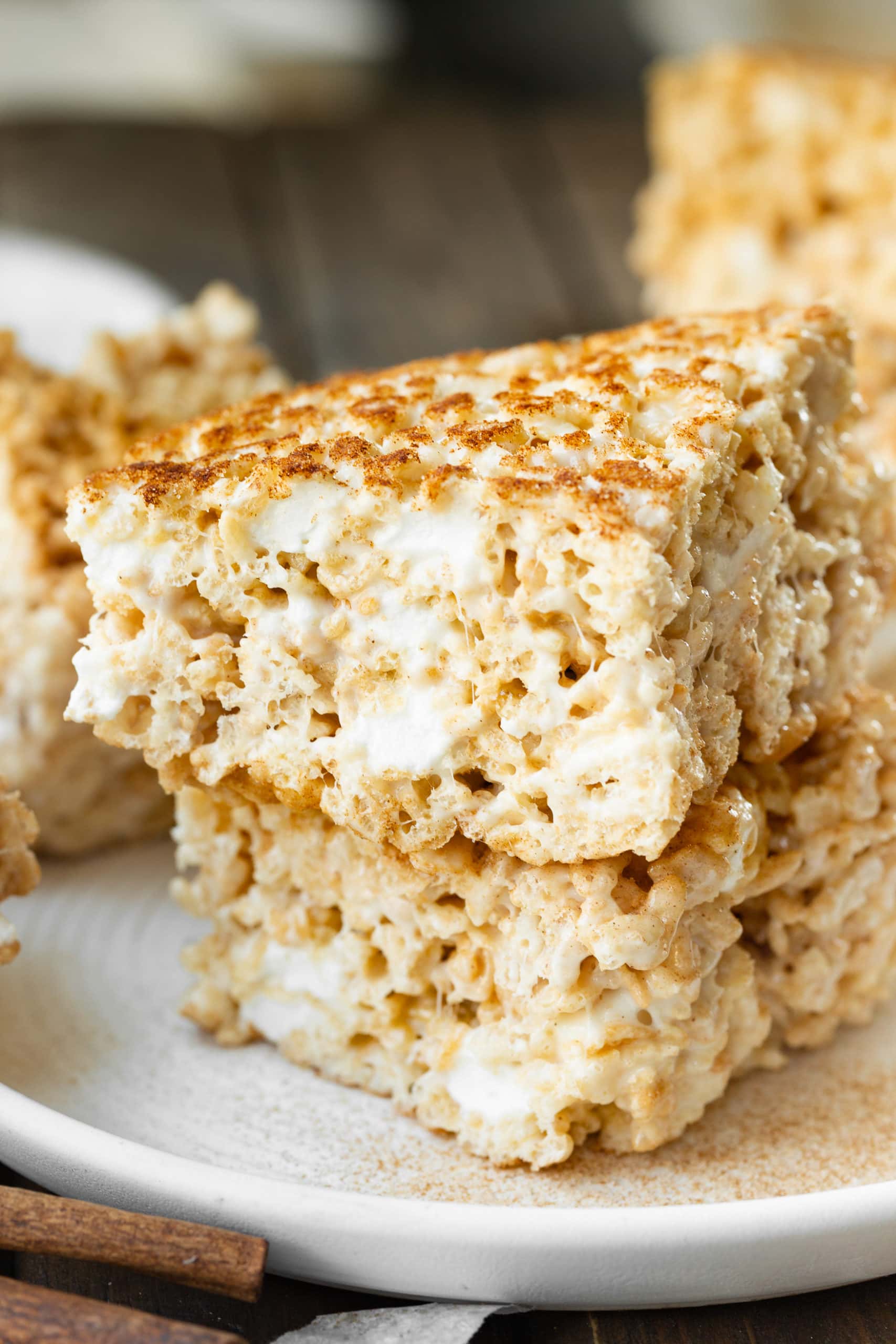 a photo of a two thick rice krispie treats topped in cinnamon sugar and stacked on top of each other so you can see the cross-sections of the treats. a photo of a two thick rice krispie treats topped in cinnamon sugar and stacked on top of each other so you can see the cross-sections of the treats.
