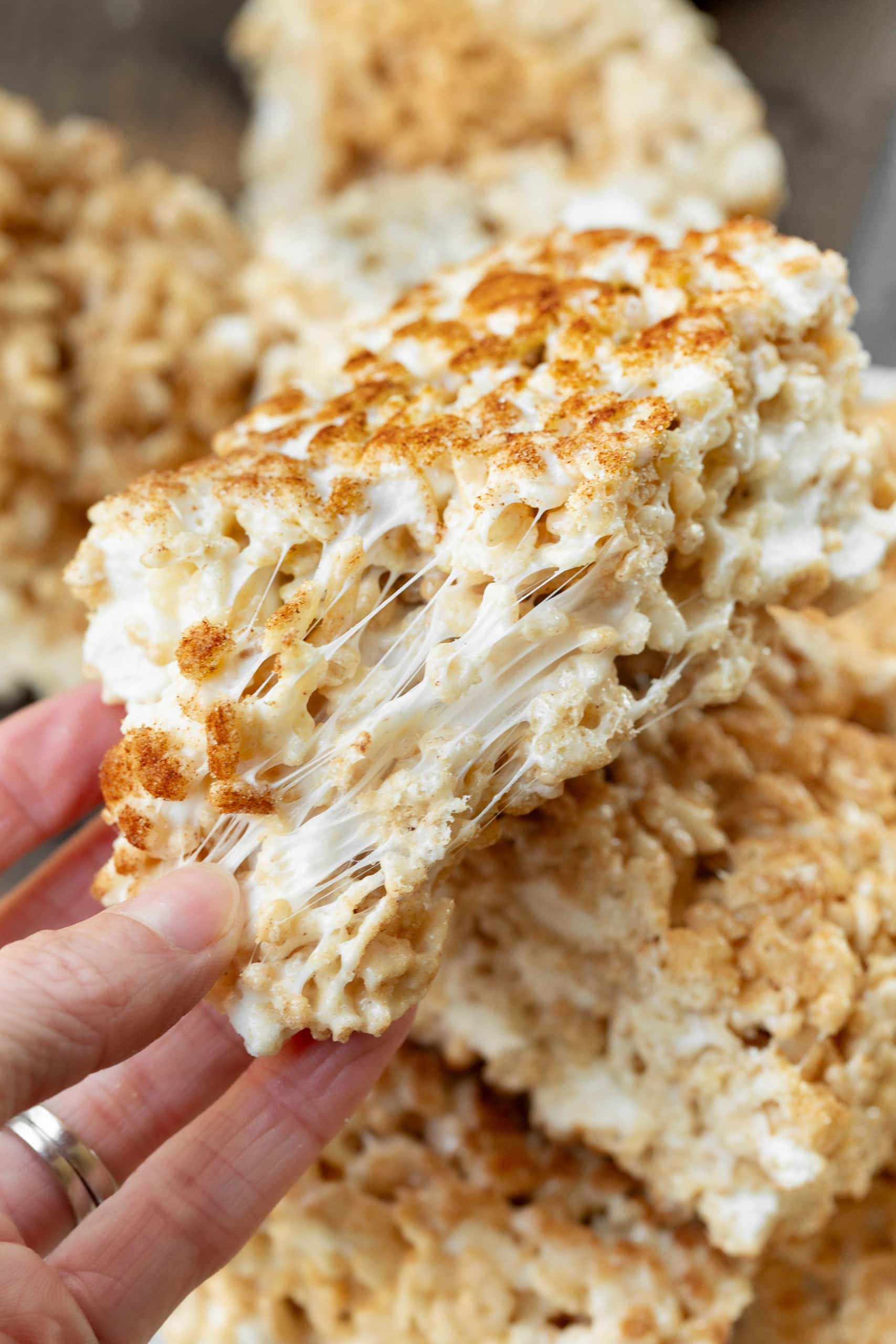 a photo of a single rice krispie treat being pulled apart by someone's hands showing the gooey marshmallow inside. a photo of a single rice krispie treat being pulled apart by someone's hands showing the gooey marshmallow inside.