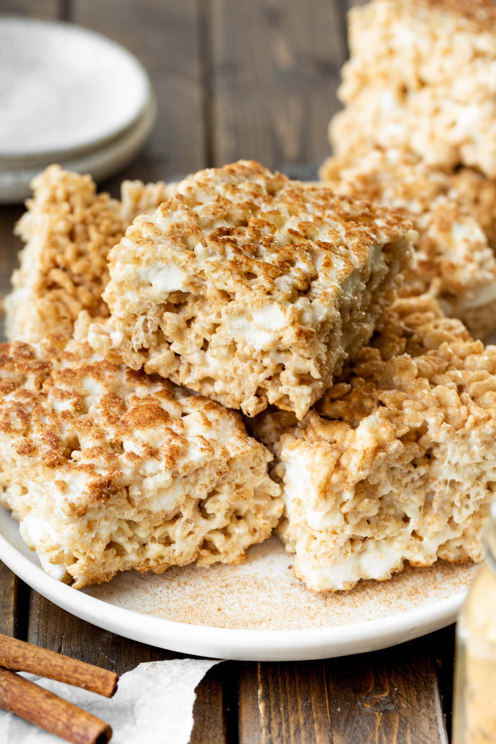 a photo of a pile of thick and gooey cinnamon sugar rice krispie treats sitting on a serving plate. a photo of a pile of thick and gooey cinnamon sugar rice krispie treats sitting on a serving plate.