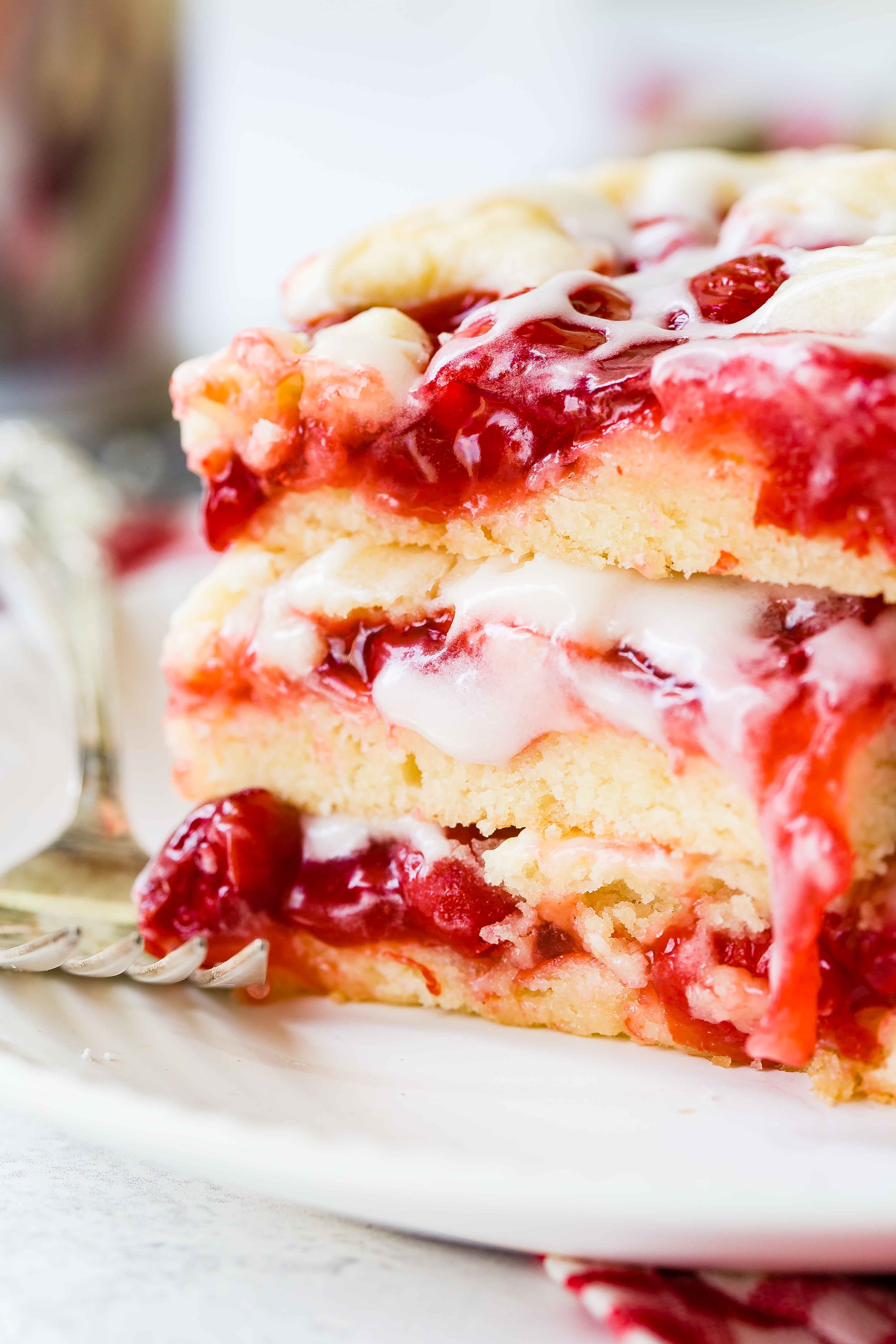 a stack of three cherry pie bars with sweet glaze dripping down. 