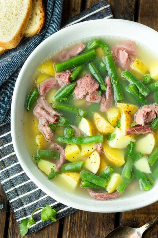 a photo of a bowl of ham hock soup loaded with potatoes, green beans and chunks of ham a photo of a bowl of ham hock soup loaded with potatoes, green beans and chunks of ham