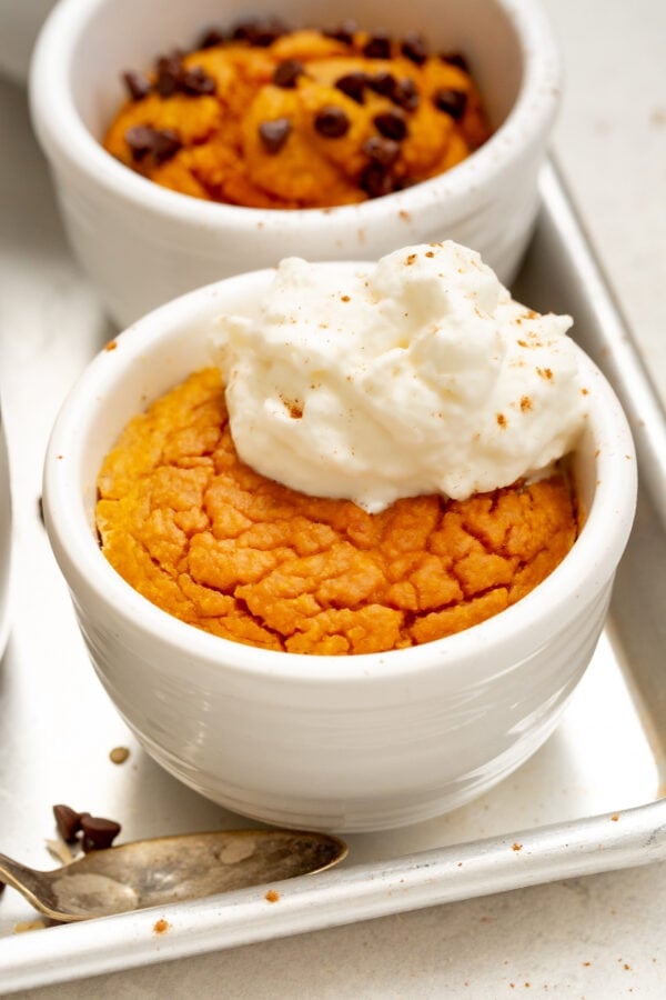 a photo of a pumpkin mug cake baked and topped with a dollop of whipped cream a photo of a pumpkin mug cake baked and topped with a dollop of whipped cream