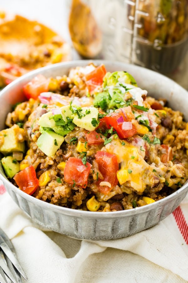 A photo of instant pot ground beef burrito bowl stopped with chopped tomatoes, avocado chunks, and chopped fresh cilantro. A photo of instant pot ground beef burrito bowl stopped with chopped tomatoes, avocado chunks, and chopped fresh cilantro.