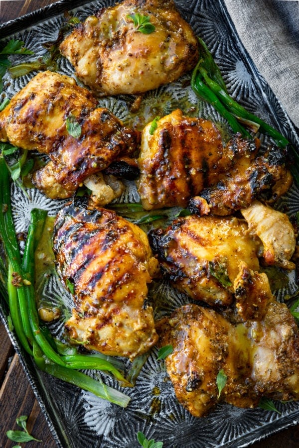 a photo of a several grilled chicken thighs sitting on a baking sheet covered in a juicy maple mustard marinade. a photo of a several grilled chicken thighs sitting on a baking sheet covered in a juicy maple mustard marinade.