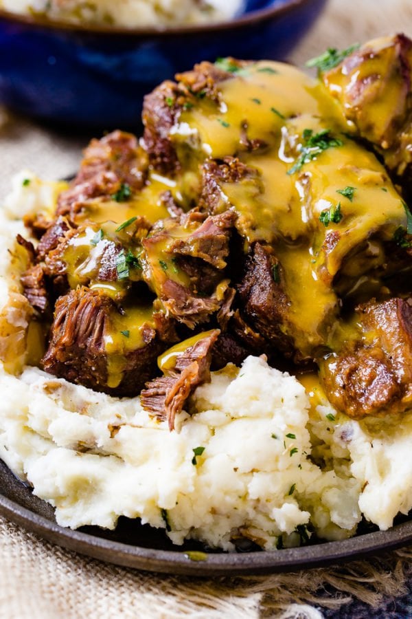 A photo of beef short ribs smothered in mustard Carolina BBQ sauce over a pile of mashed potatoes. A photo of beef short ribs smothered in mustard Carolina BBQ sauce over a pile of mashed potatoes.