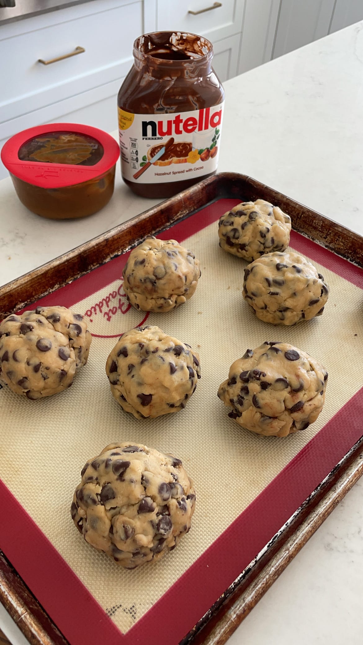 Chocolate chip cookie dough stuffed with nutella and caramel and then pinched closed to bake Chocolate chip cookie dough stuffed with nutella and caramel and then pinched closed to bake