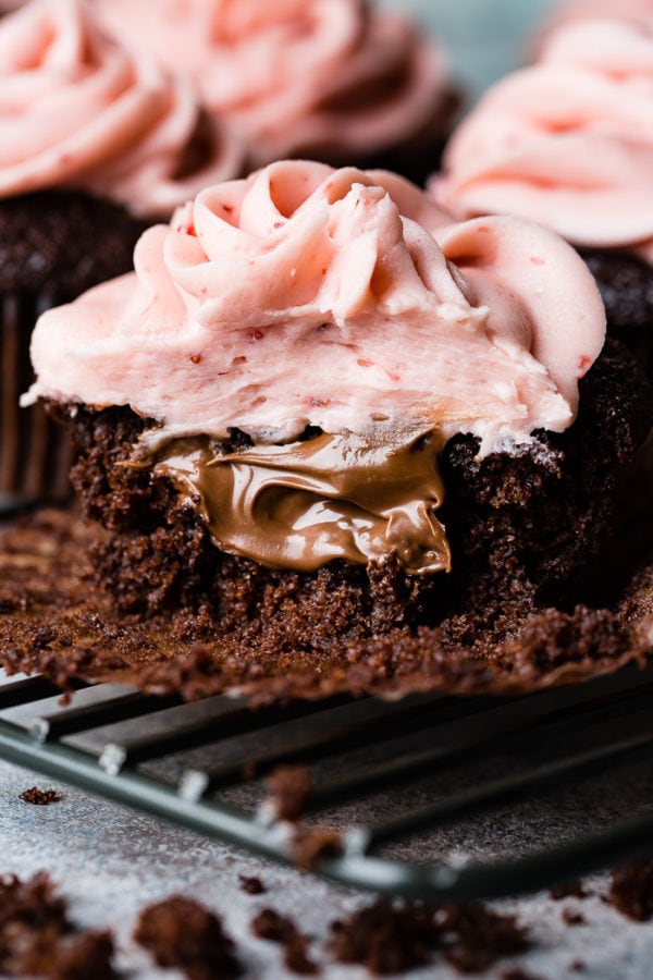 a close up of a nutella stuffed chocolate cupcake with strawberry buttercream frosting a close up of a nutella stuffed chocolate cupcake with strawberry buttercream frosting