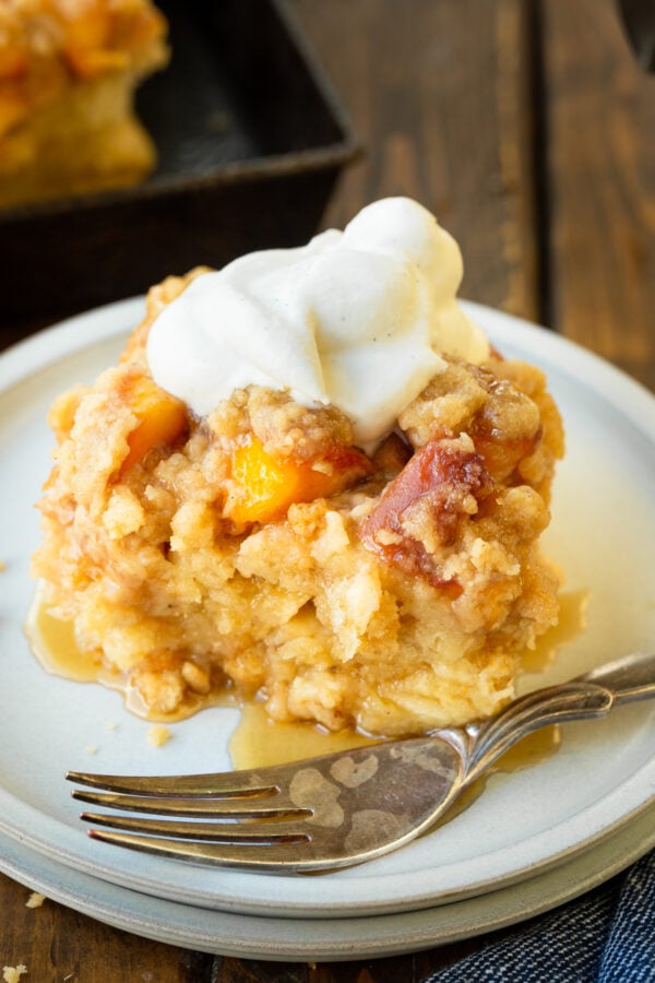 a photo of a serving of golden baked peach cobbler french toast casserole topped with a dollop of whipped cream a photo of a serving of golden baked peach cobbler french toast casserole topped with a dollop of whipped cream