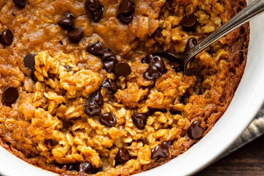 a pumpkin chocolate chip baked oatmeal with a spoon scooping up a serving a pumpkin chocolate chip baked oatmeal with a spoon scooping up a serving