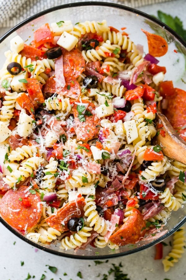 A glass bowl of quick and easy italian pasta salad recipe with homemade italian dressing. Rotini pasta with pepperoni, salsami, black olives, parmesan cheese, mozzarella cheese, peppers, dressing and red onions! A glass bowl of quick and easy italian pasta salad recipe with homemade italian dressing. Rotini pasta with pepperoni, salsami, black olives, parmesan cheese, mozzarella cheese, peppers, dressing and red onions!