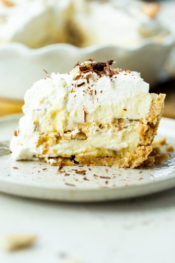 a photo of a large slice of double layered banana pudding pie topped with whipped cream and shaved chocolate a photo of a large slice of double layered banana pudding pie topped with whipped cream and shaved chocolate