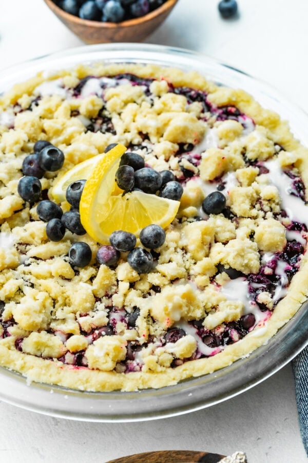 a photo of a whole baked wild blueberry pie in a shortbread crust with a streusel topping and a vanilla glaze. a photo of a whole baked wild blueberry pie in a shortbread crust with a streusel topping and a vanilla glaze.