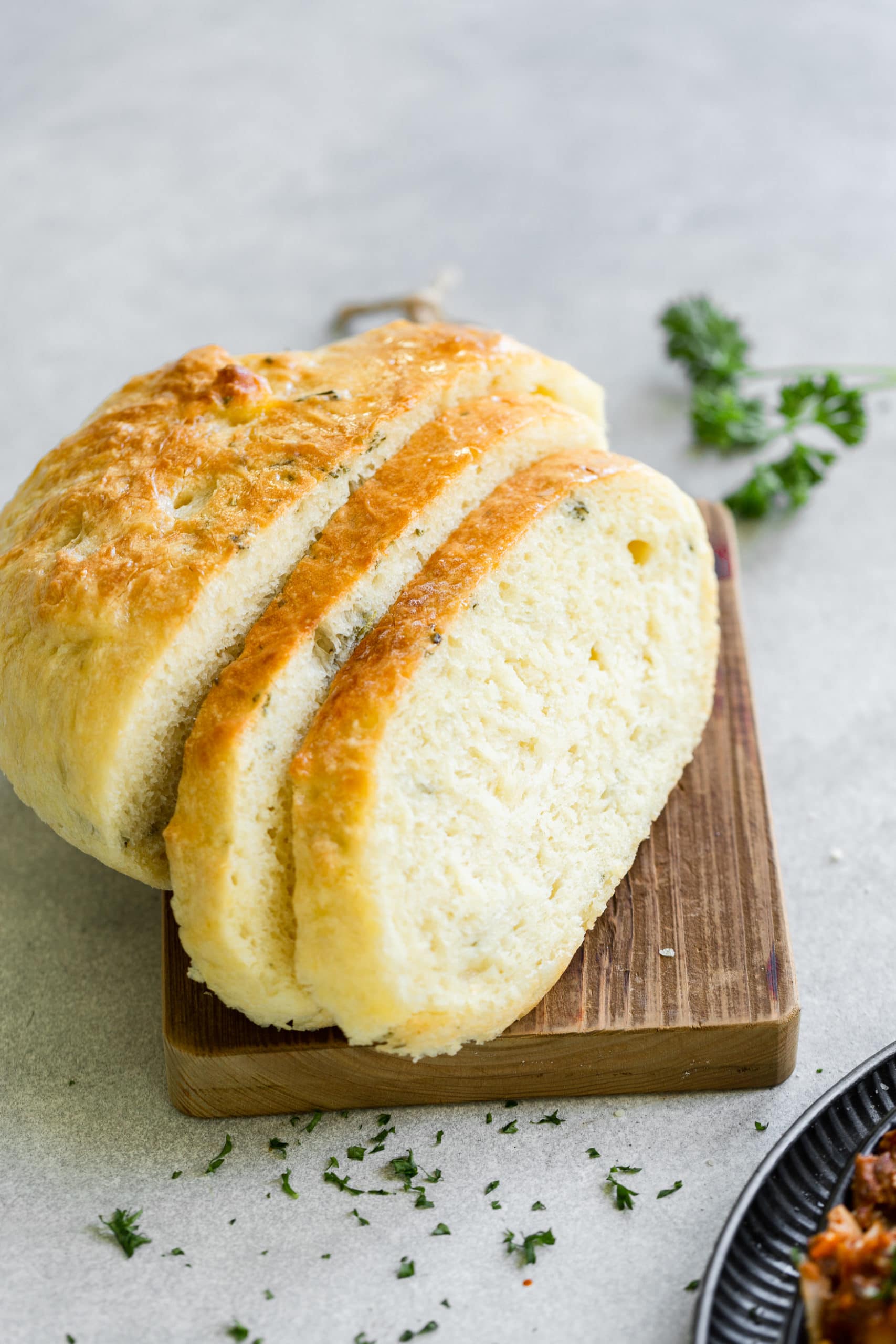 a photo of a loaf of baked peasant bread that has been sliced in half with a couple more slices of bread leaning against it and they are all sitting on a wooden cutting board. a photo of a loaf of baked peasant bread that has been sliced in half with a couple more slices of bread leaning against it and they are all sitting on a wooden cutting board.