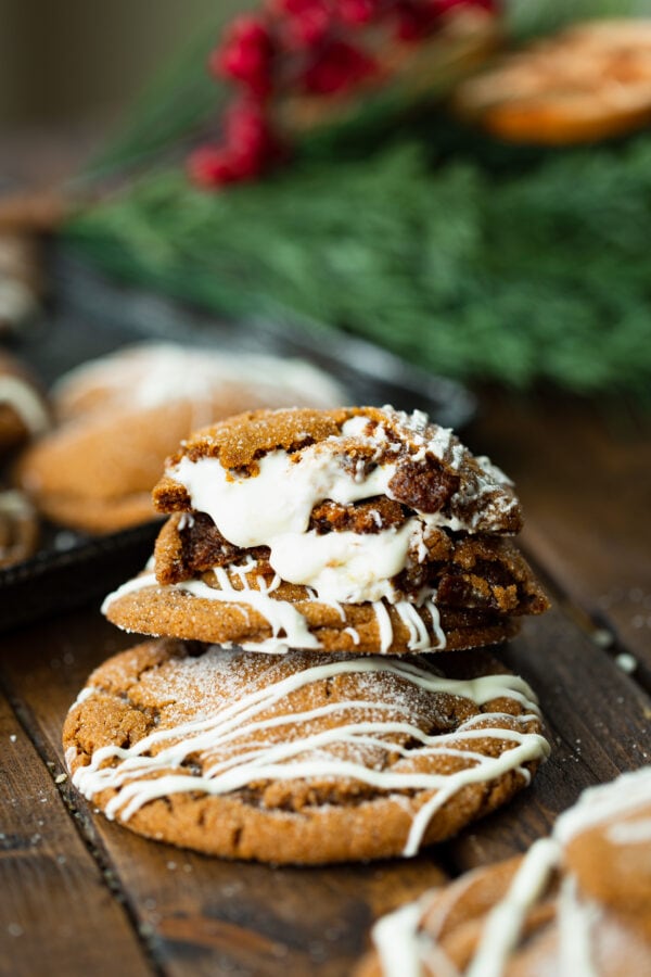 a photo of a stack of soft molasses cookies that are stuffed with melty white chocolate. the top cookie has been broken in half so you can see the inside of the cookie and the white chocolate is melting out. a photo of a stack of soft molasses cookies that are stuffed with melty white chocolate. the top cookie has been broken in half so you can see the inside of the cookie and the white chocolate is melting out.