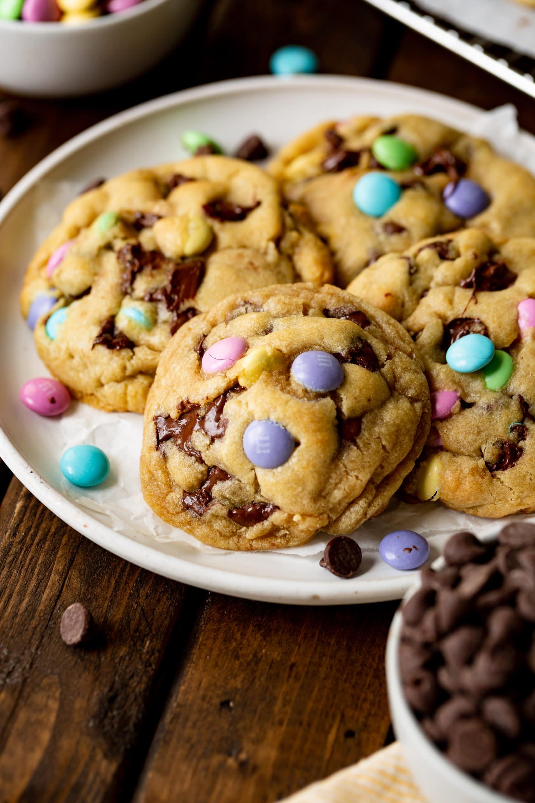 a photo of a white serving plate full of thick and golden Easter m&m chocolate chip cookies. a photo of a white serving plate full of thick and golden Easter m&m chocolate chip cookies.