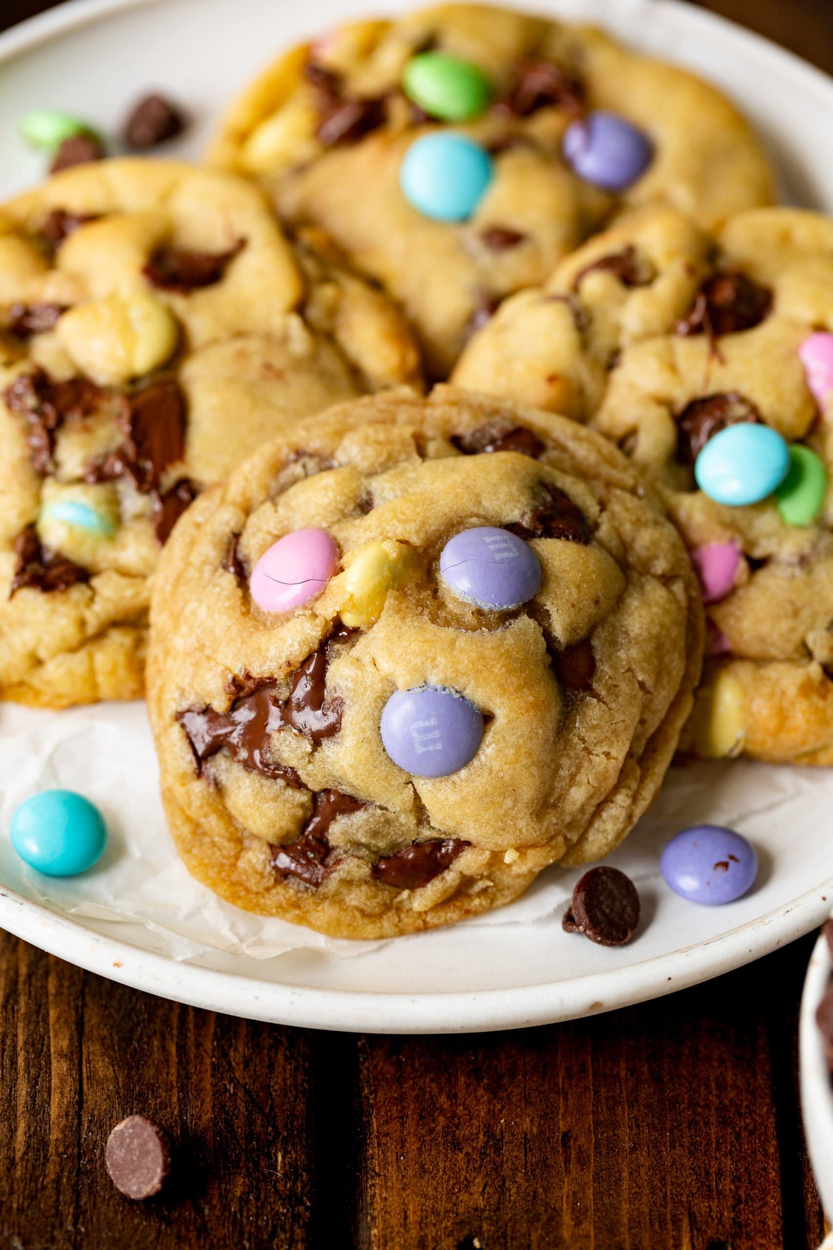 a photo of a white serving plate full of thick and golden Easter m&m chocolate chip cookies. a photo of a white serving plate full of thick and golden Easter m&m chocolate chip cookies.