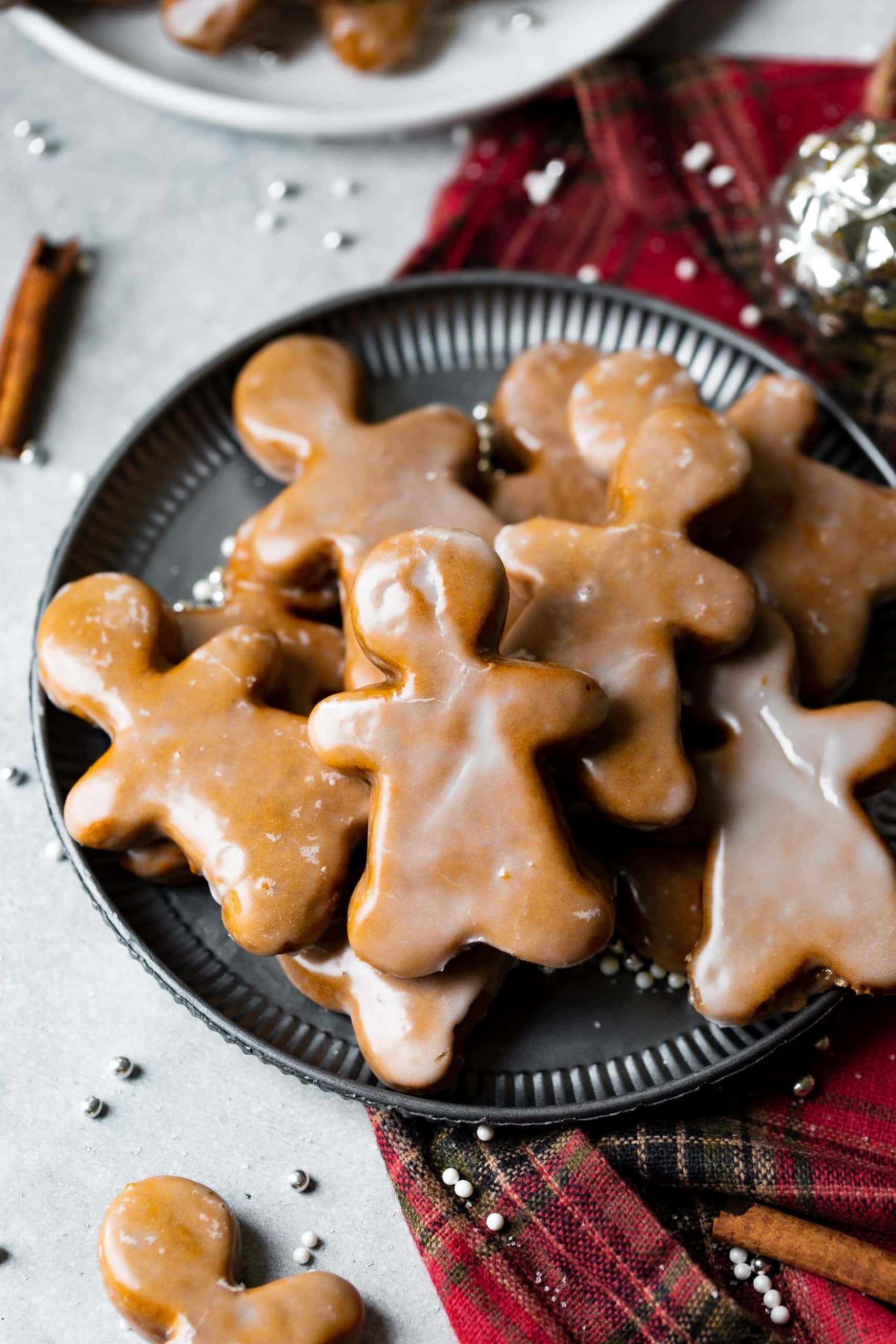 a photo of a plate full of thick and chewy gingerbread men cookies covered in a light glaze. a photo of a plate full of thick and chewy gingerbread men cookies covered in a light glaze.
