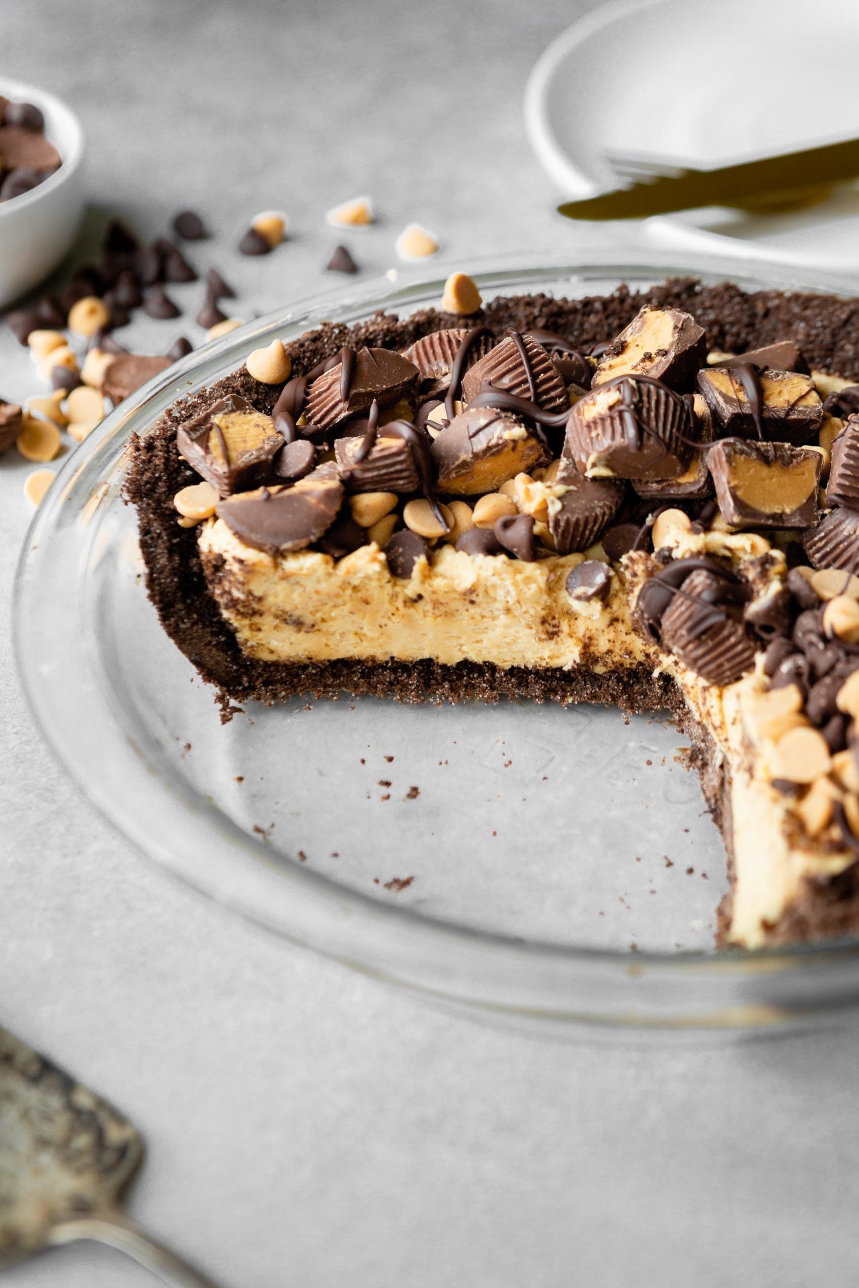 a photo of a peanut butter pie in a glass pie plate and a few pieces have been removed from the pie. a photo of a peanut butter pie in a glass pie plate and a few pieces have been removed from the pie.