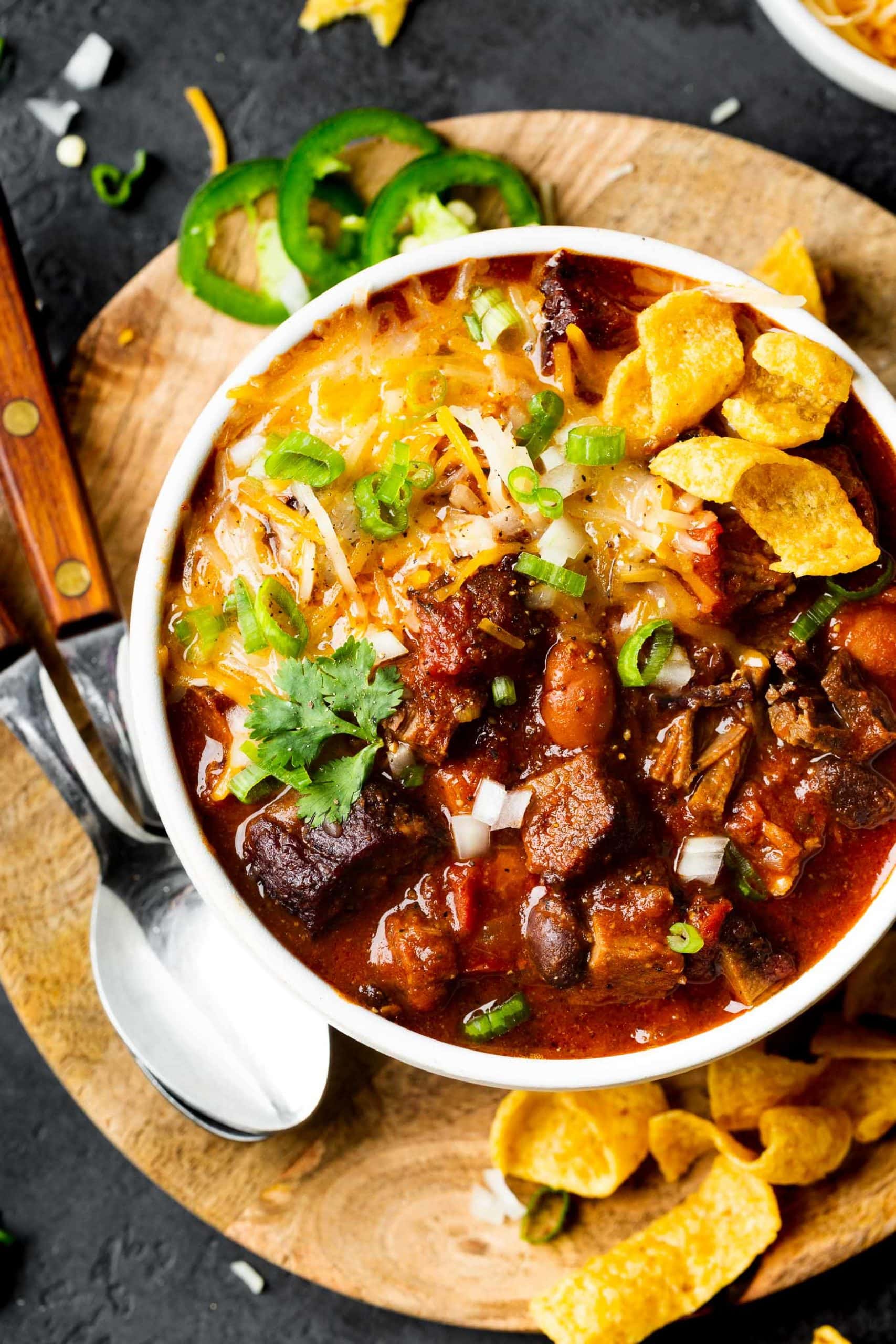 a photo of a large bowl of chili topped with fritos, cilantro, and diced onions. a photo of a large bowl of chili topped with fritos, cilantro, and diced onions.