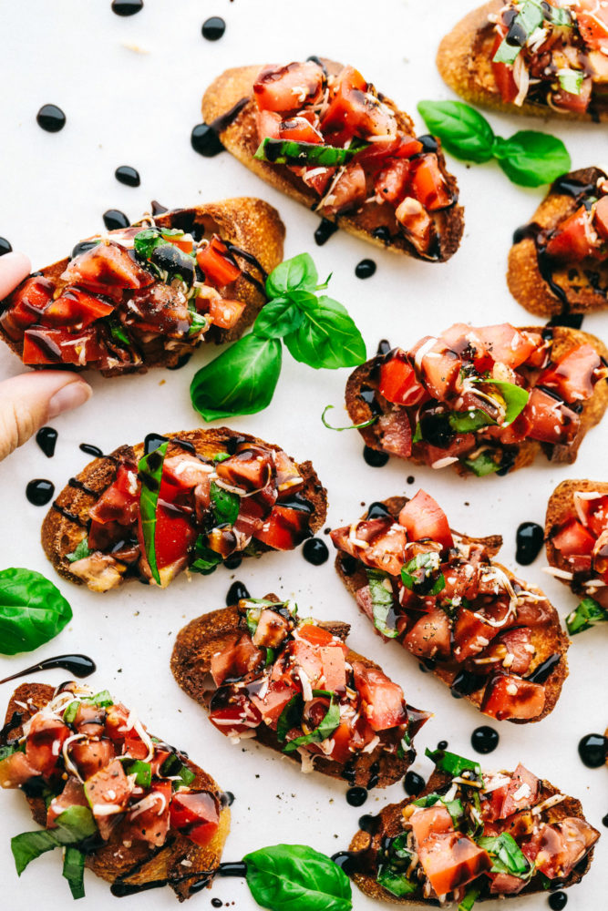 Bruschetta toast on a white countertop garnished with cilantro. 